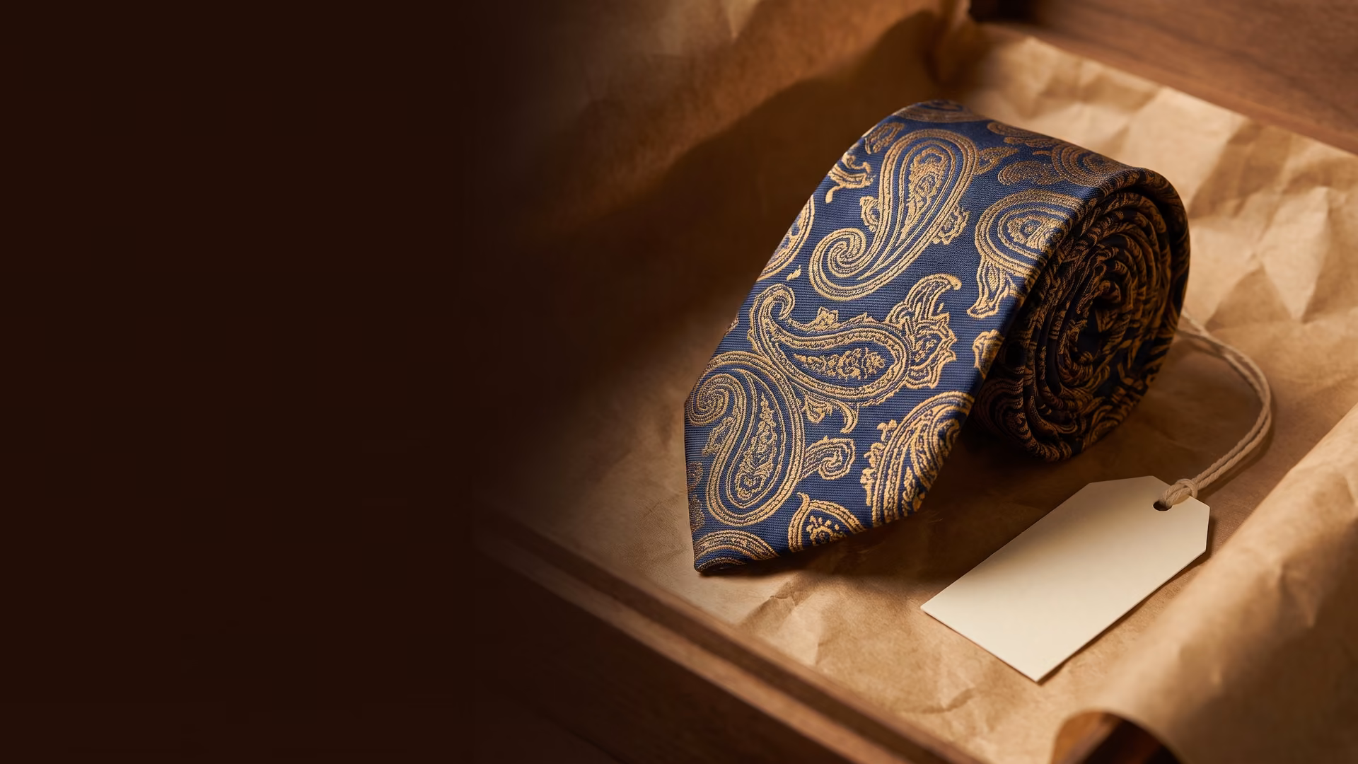 Gravata paisley azul e dourada enrolada sobre papel kraft